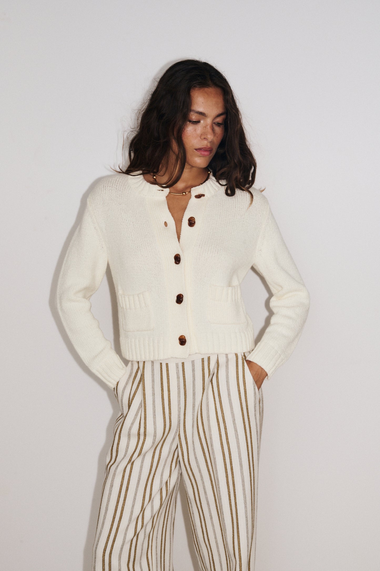 Zoom sur les détails du gilet Aza Stella Forest en maille douce coloris écru, fermeture boutonnée et poches plaquées.